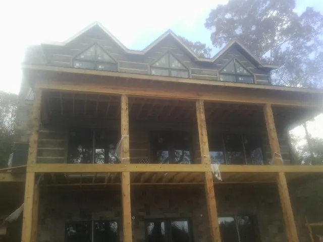 Dormers and porch framing on a large log home under construction — Roof Coating work by our crew in Bon Secour